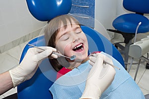 A close-up of a dentistÃ¢â¬â¢s hands and a child with an opened mouth photo